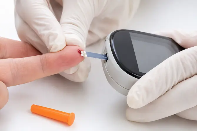 Profesional de salud aplicando muestra de sangre en tira reactiva de glucosa insertada en glucómetro
