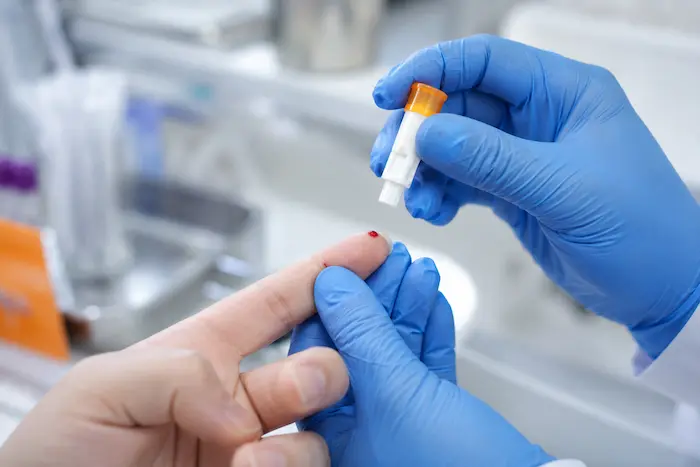 Lanceta de laboratorio en el momento de la punción para obtener sangre capilar